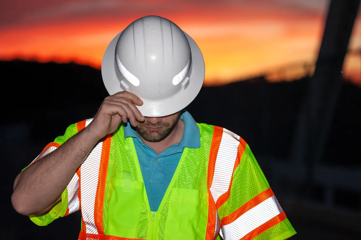 worker wearing hardhat standing against sky sunset